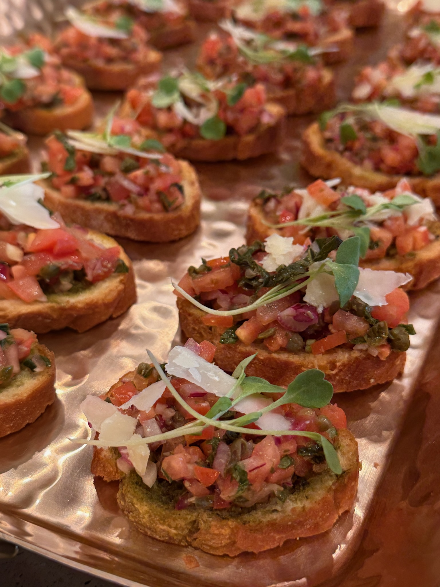 Bruschetta with shaved parmesan and microgreens on a copper tray